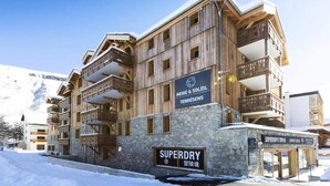 Ein mehrstöckiges Hotel mit hölzernen Balkonen und einem Schild mit dem Schriftzug 'Superdry'.
