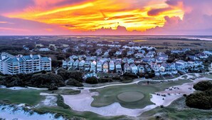 Ein Resort mit mehreren Gebäuden, einem Golfplatz und Blick auf den Sonnenuntergang.