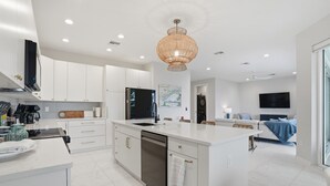 Una cocina moderna con armarios blancos, una isla grande y una lámpara colgante.