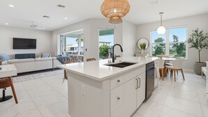 Una cocina moderna con una isla central, armarios blancos y un comedor con mesa y sillas.