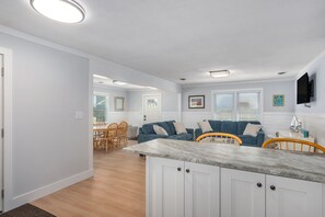 Une cuisine moderne avec des meubles blancs, un plan de travail en marbre et un coin repas doté de chaises en bois.