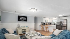 Una sala de estar moderna con sofá, mesa de centro y televisor montado en la pared.