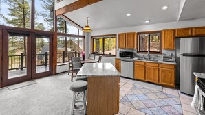 Une cuisine spacieuse avec des meubles en bois, un grand îlot central et une vue sur l’extérieur.