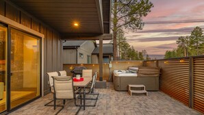 An outdoor patio with a table and chairs, a hot tub, and a view of the sky.