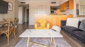 Una sala de estar moderna con un sofá, un sillón amarillo, una mesa de centro y un comedor con sillas y una mesa.
