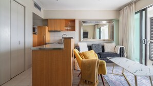 Una cocina moderna con armarios de madera, una isla central y una zona de comedor con mesa de mármol.