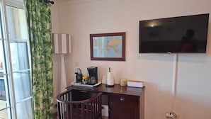 A room with a desk, chair, coffee maker, and a TV on the wall. - Building Martinique (Sainte-Luce)