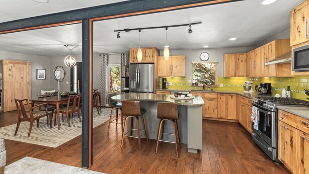 A modern kitchen with wooden cabinets, a stainless steel refrigerator, and a central island with bar stools. - Pet Friendly|Steps from Town|Private yard (Steamboat Springs)