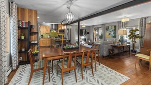 A spacious living room with a wooden dining table, comfortable seating, and a large window offering a view of the outdoors. - Pet Friendly|Steps from Town|Private yard (Steamboat Springs)