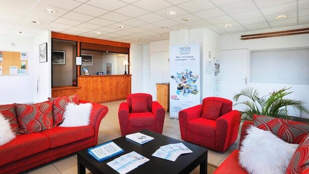 Eine Lobby mit roten Sofas, einem Empfangstresen und einem Poster an der Wand.