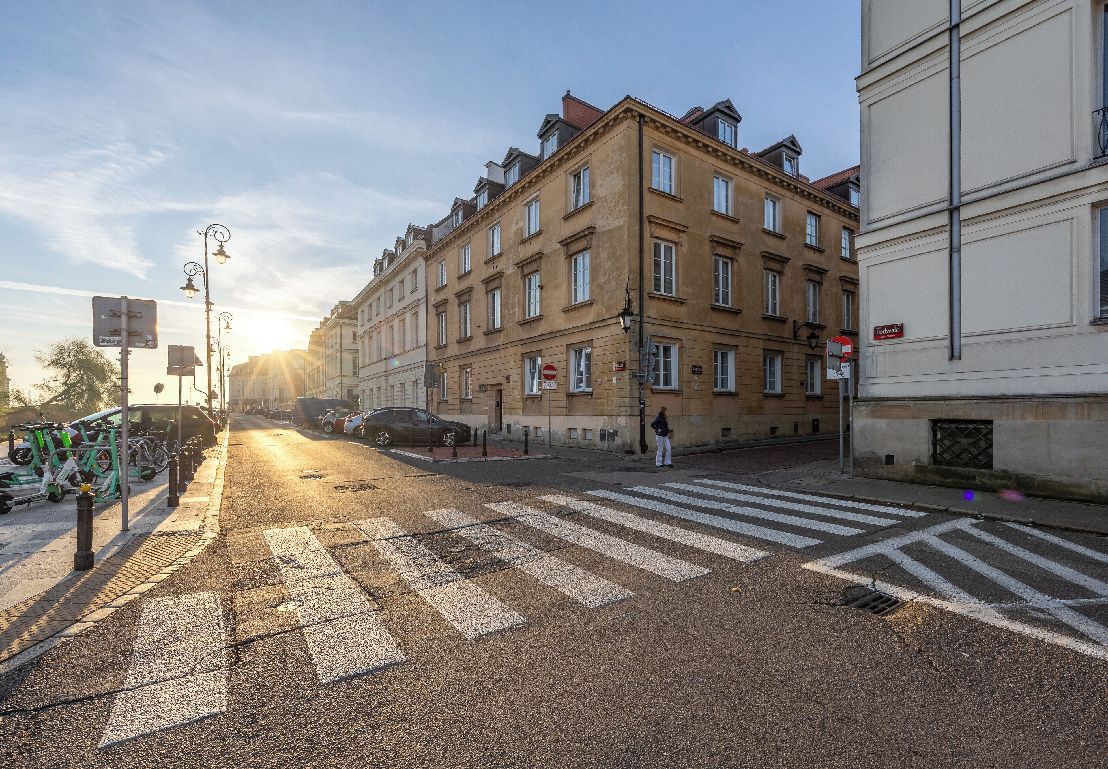 Straatbeeld met zebrapad, geparkeerde fietsen en klassieke architectuur.