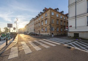 Una vista di strada con un attraversamento pedonale, biciclette parcheggiate e architettura classica.