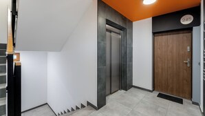 Un ascenseur moderne doté d’un écran numérique, d’une porte en bois et d’une plaque indiquant le numéro de la chambre : 245.