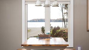 A dining table with a view of a lake and trees. - The Long Lake Escape (Traverse City)