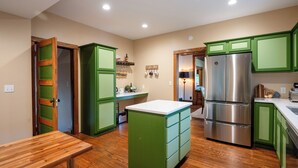 A kitchen with green cabinets, a stainless steel refrigerator, and a wooden bench. - Updated Home near downtown Grand Haven - First Floor (Grand Haven)