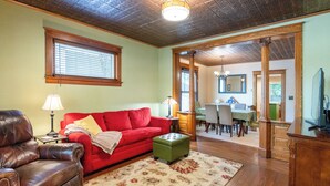 A living room with a red sofa, a brown leather chair, a green ottoman, and a patterned rug. - Updated Home near downtown Grand Haven - First Floor (Grand Haven)