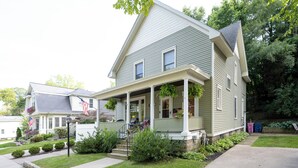 A two-story house with a porch, a front yard, and a small garden. - Updated Home near downtown Grand Haven - First Floor (Grand Haven)