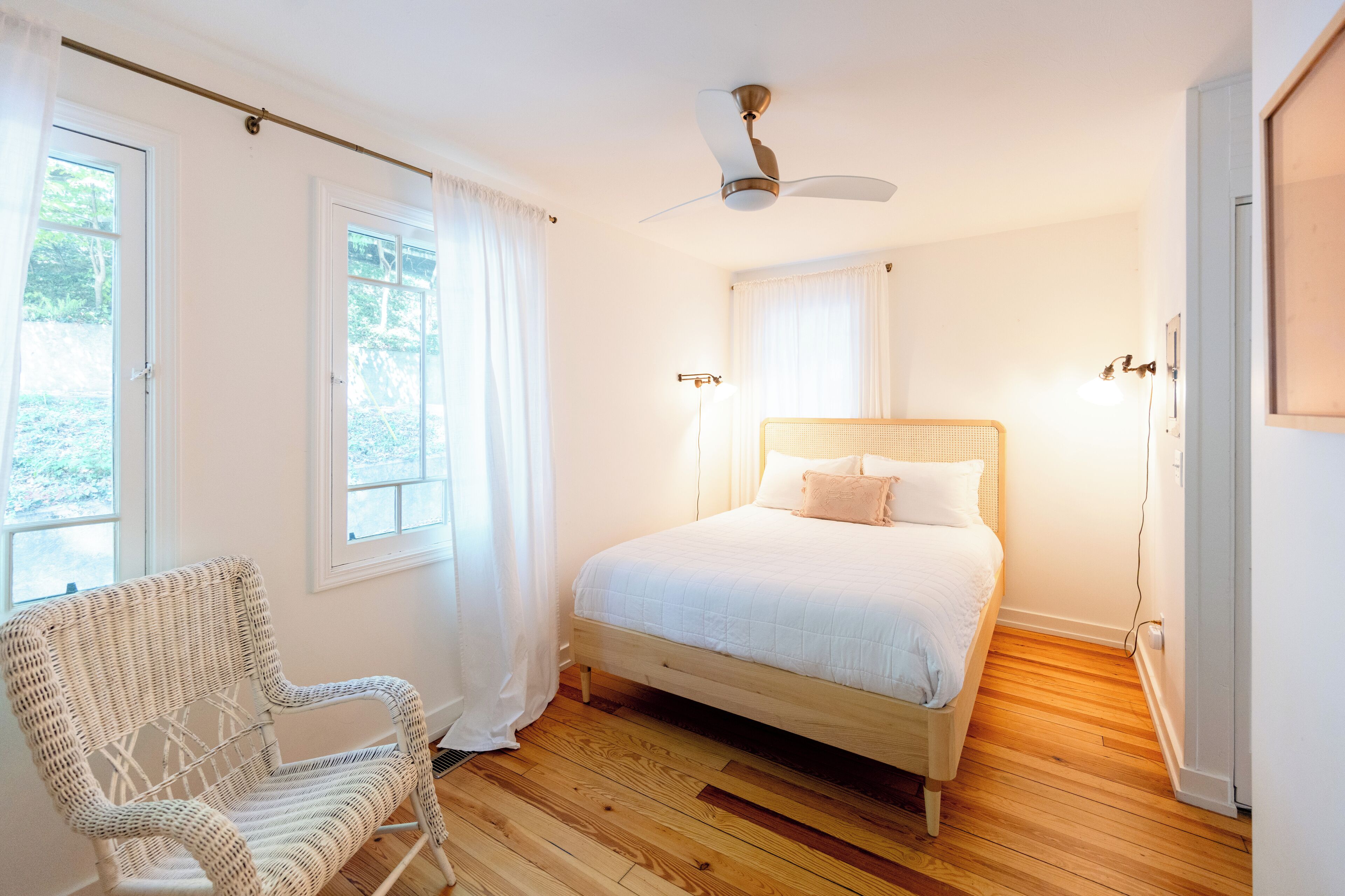 Una camera da letto con un letto, una sedia e una ventola a soffitto.