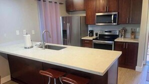 A modern kitchen with a central island, stainless steel appliances, and wooden cabinets.