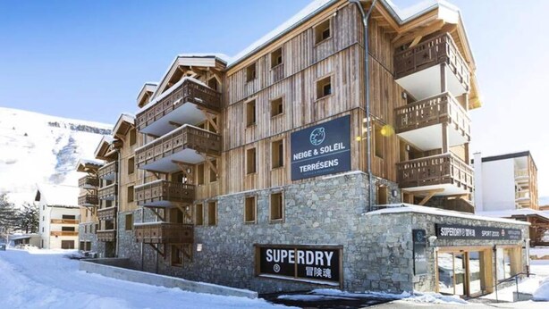 Ein mehrstöckiges Hotel mit hölzernen Balkonen und einem Schild mit dem Schriftzug 'Superdry'.