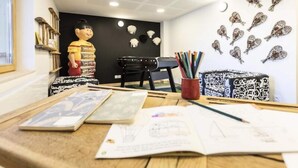 Ein Arbeitsplatz mit Schreibtisch, Zeichenmaterialien und einem schwarzen Stuhl.