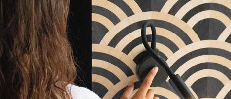 A person in a white robe adjusting a black device on a wall with a wave pattern.