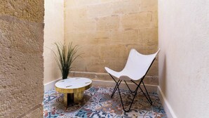 A corner with a white chair, a small round table, and a potted plant against a textured wall. - Caracalla Room with private patio (Bordeaux)