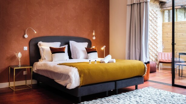 A modern bedroom with a large bed, a bedside table, a lamp, and a view of the outdoors through a glass door. - Large Magna room with private terrace (Bordeaux)