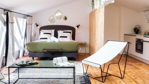 A modern bedroom with a skylight, a bed with a green bedspread, a small table with a tray, a whiteboard, and a kitchenette in the corner. - Lixus Suite with private terrace and kitchen (Bordeaux)