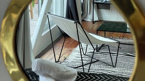 A room with a hammock, a small table with a plant, and a view of the outdoors through a window with curtains. - Lixus Suite with private terrace and kitchen (Bordeaux)