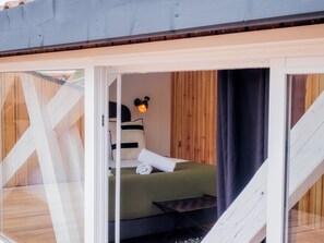 A cozy bedroom with a bed, pillows, a nightstand, and a wall-mounted lamp. - Lixus Suite with private terrace and kitchen (Bordeaux)
