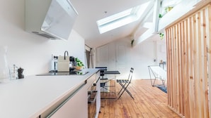 A modern kitchen with a central island, a dining area with a table and chairs, and a wooden partition. - Lixus Suite with private terrace and kitchen (Bordeaux)