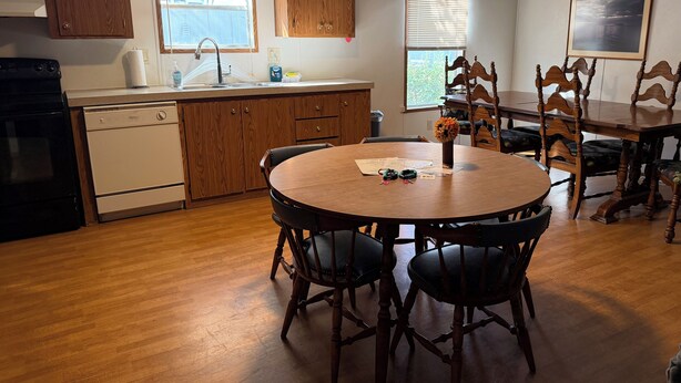 A kitchen with wooden cabinets, a sink, and a dining table with chairs. - Lakeside Valentine (Kingsland)
