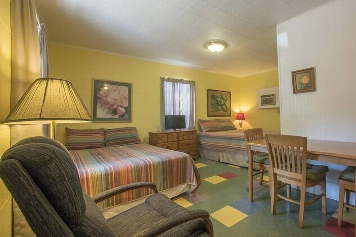 A room with a bed, a desk, a chair, a lamp, and a television.