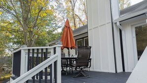 Een terras met een tafel, stoelen, een parasol en een trap naar een huis.