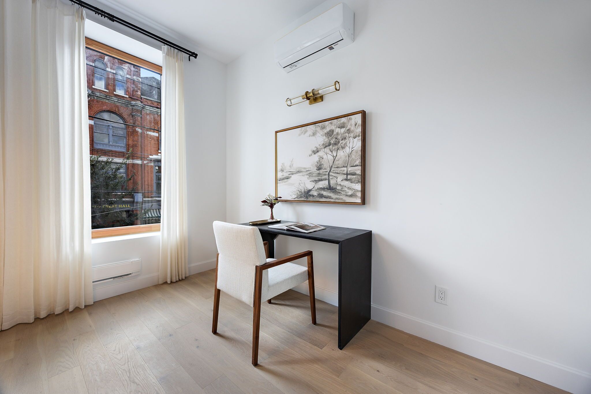 Una habitación con escritorio, silla y ventana con cortinas.