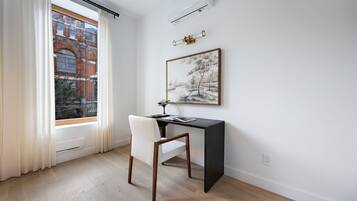 Una habitación con escritorio, silla y ventana con cortinas.