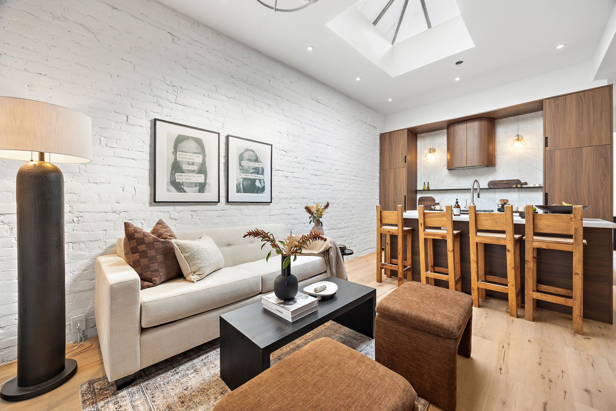 A modern living room with a sofa, coffee table, and a dining area with wooden chairs and a kitchen in the background.