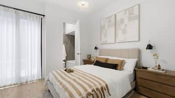 Un dormitorio con una cama grande, una mesita de noche de madera, una mesita con lámpara y vistas al baño.