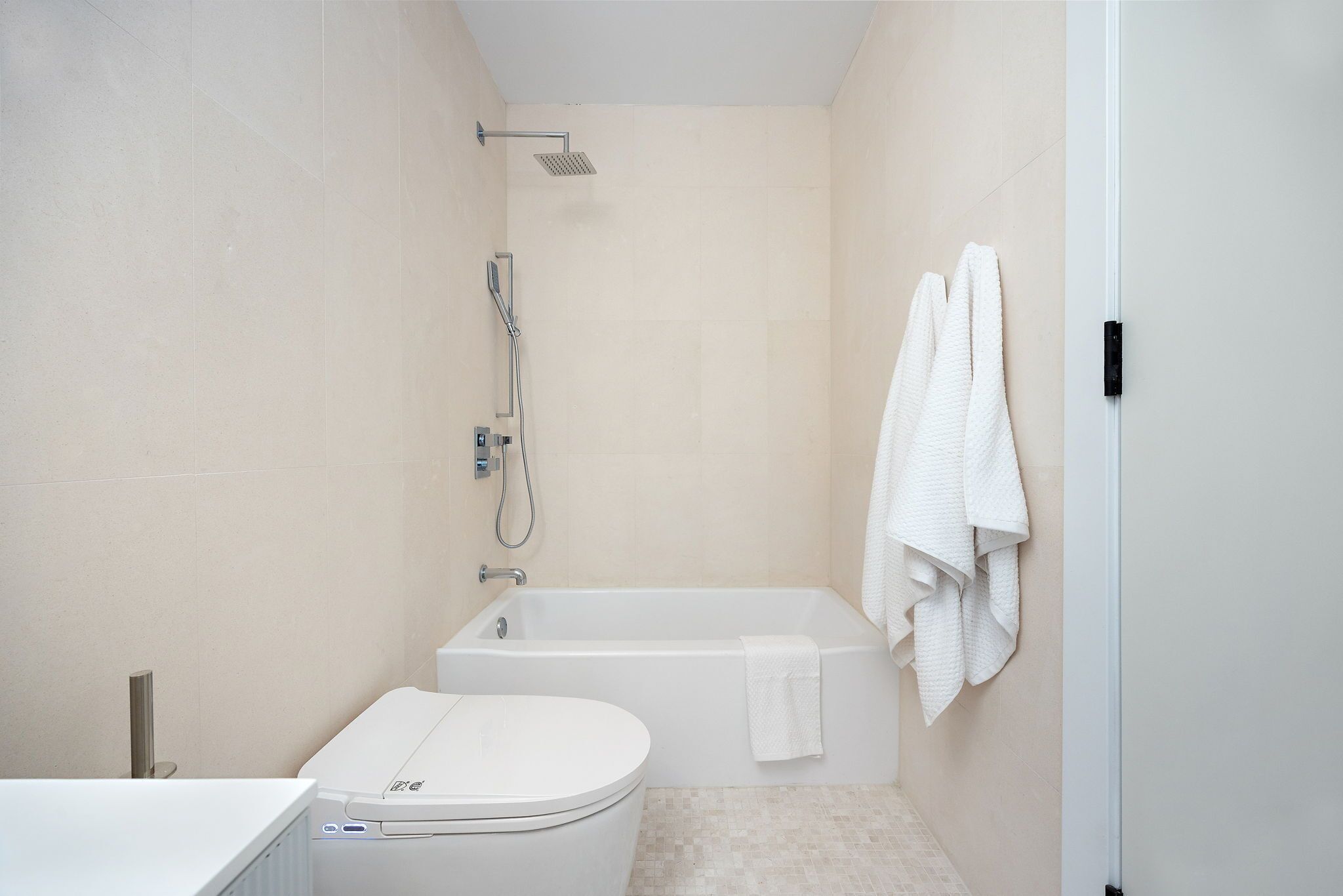 A modern bathroom with a toilet, bathtub, and shower.