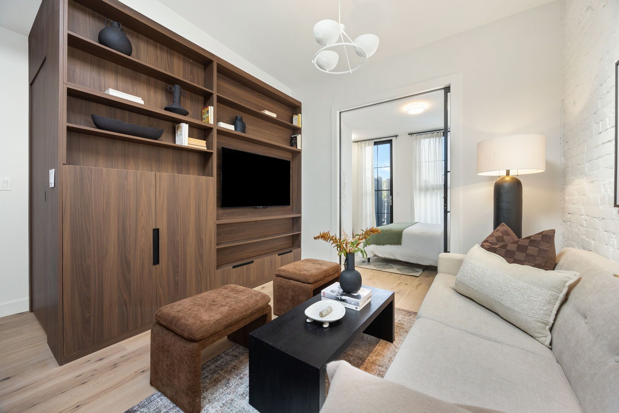 Una sala de estar moderna con un sofá, una mesa de centro y un televisor sobre un mueble de madera.