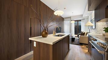 Una cocina moderna con armarios de madera oscura, una isla central, electrodomésticos de acero inoxidable e iluminación colgante.