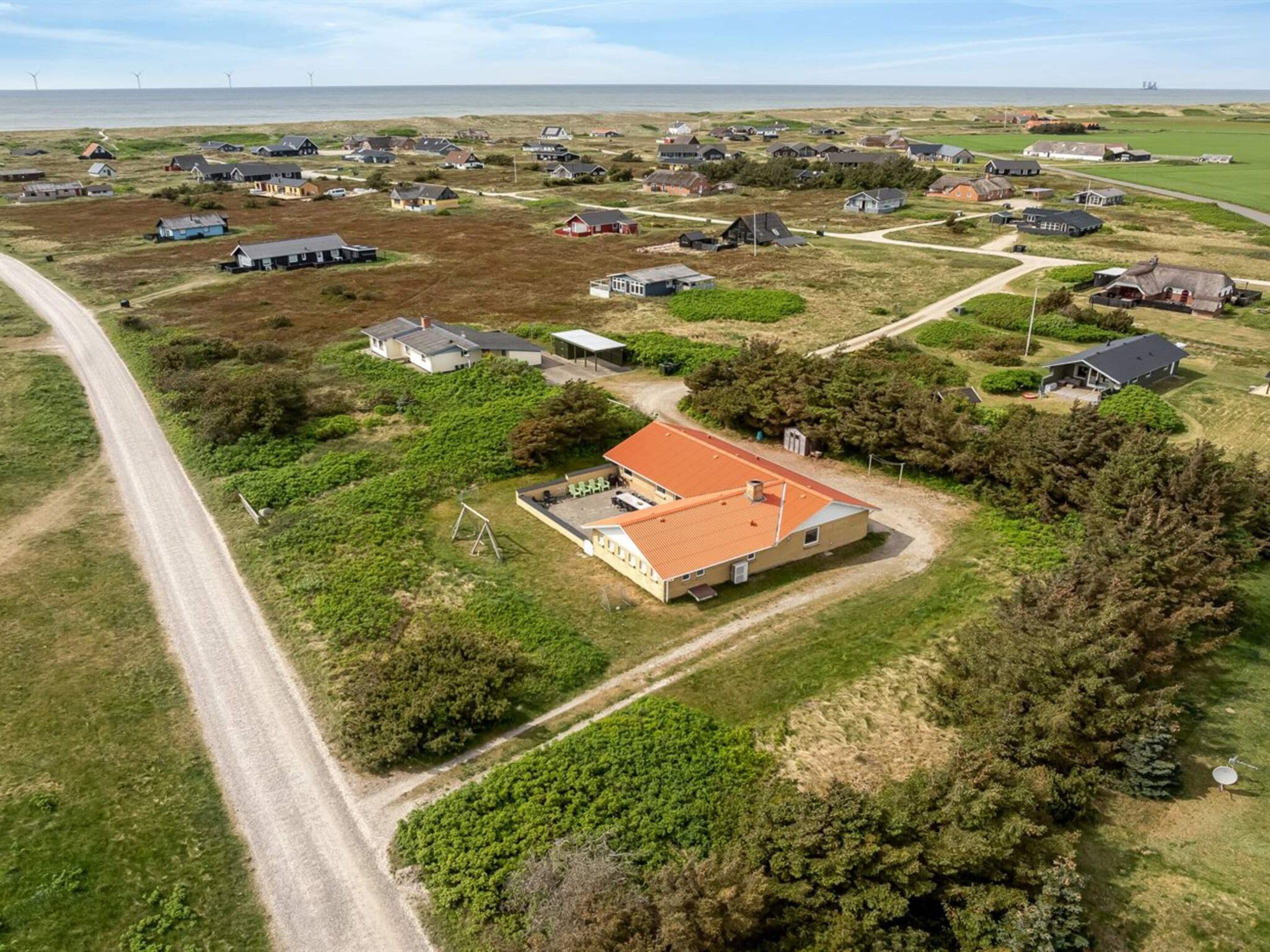 Vista aerea di una zona residenziale con case, strade e una distesa d'acqua sullo sfondo.