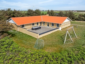 A building with a red roof, a patio with tables and chairs, and a swing set. - 4 Star Holiday Home in Harboore (Harboore)