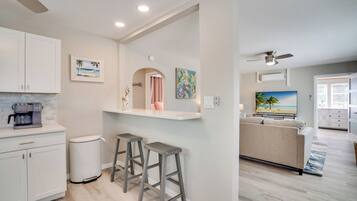A modern kitchen with white cabinets, a coffee maker, and two stools.