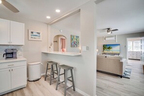Una cocina moderna con armarios blancos, una cafetera y dos taburetes.