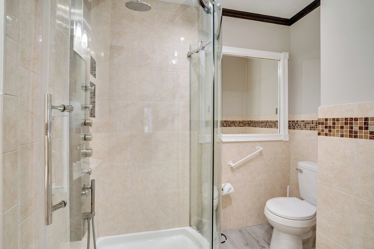 Une salle de bain avec une douche à parois de verre, des toilettes blanches et un sol carrelé.