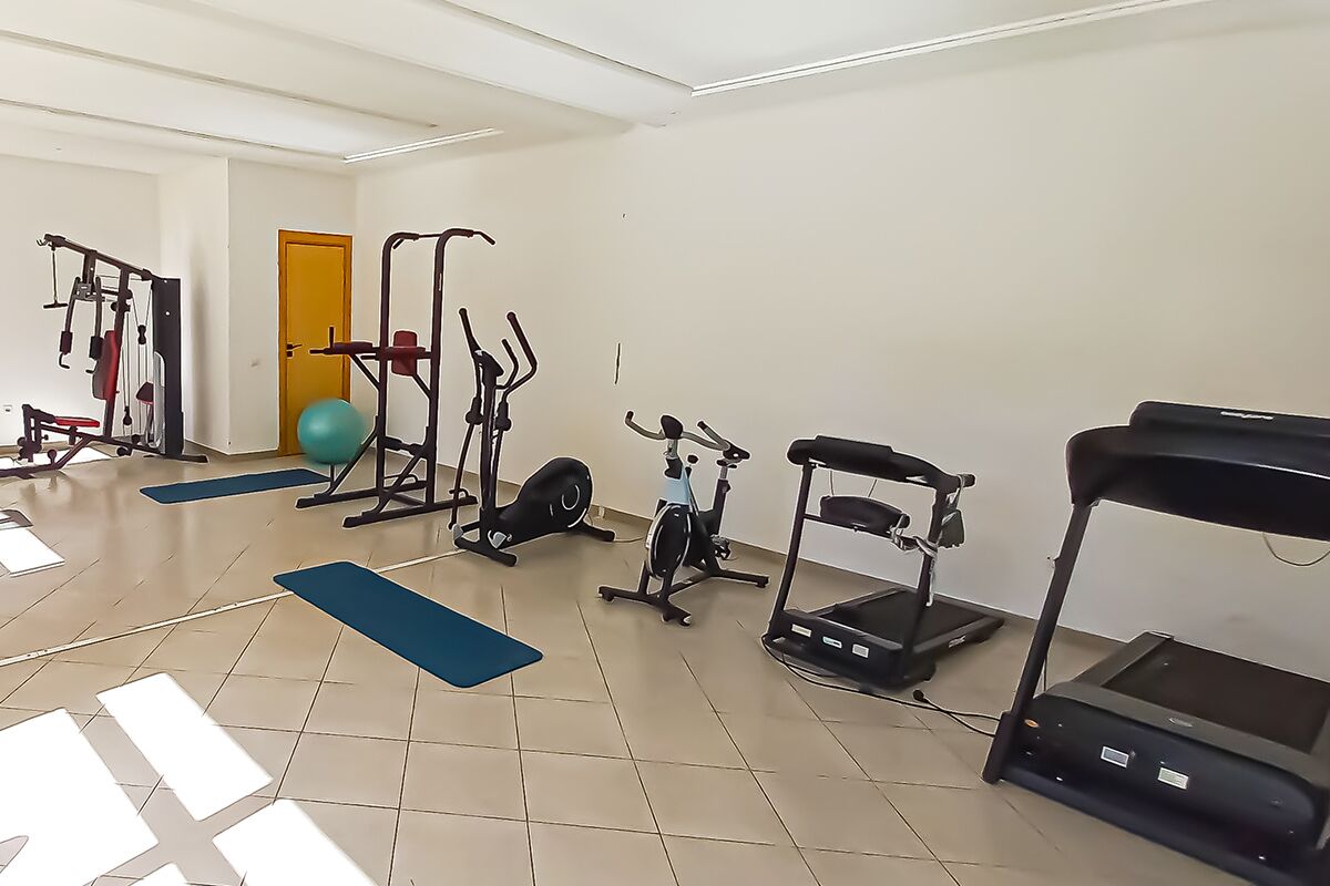 A gym with various exercise equipment including treadmills, stationary bikes, and weight machines.