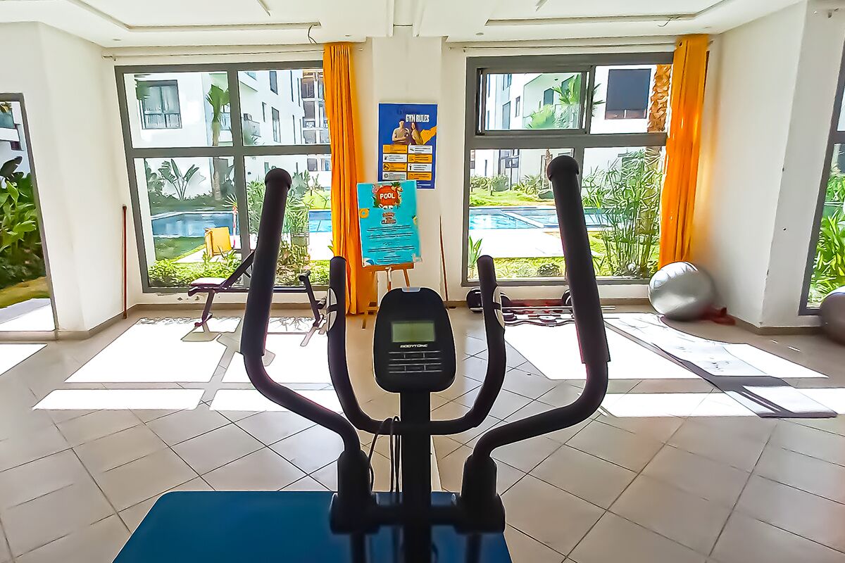 Une salle de sport intérieure équipée de matériel d’exercice, dotée de grandes fenêtres et offrant une vue sur l’extérieur.