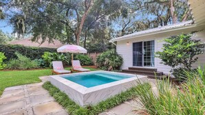 A backyard with a rectangular swimming pool, two lounge chairs, and a small patio area. - Private Cottage Oasis w Pretty Porch + Splash Pool (St Simons Island)